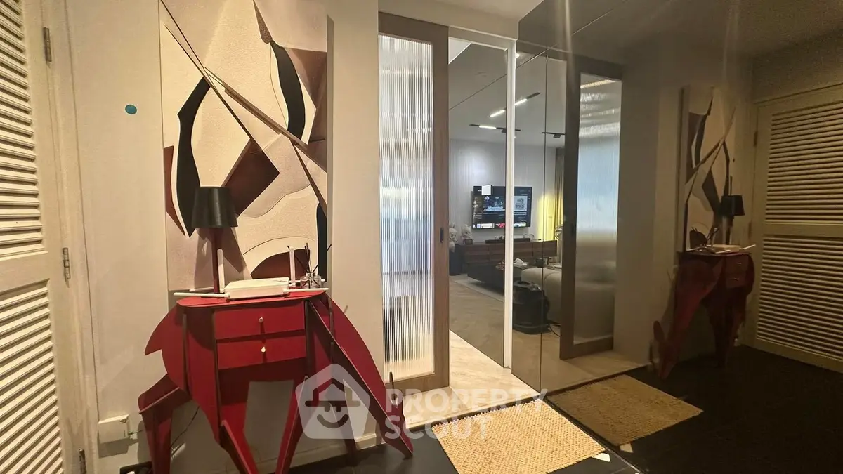 Stylish modern hallway with artistic decor and mirrored doors leading to a cozy living area.