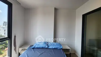 Modern bedroom with blue bedding and large window offering city views, perfect for urban living.