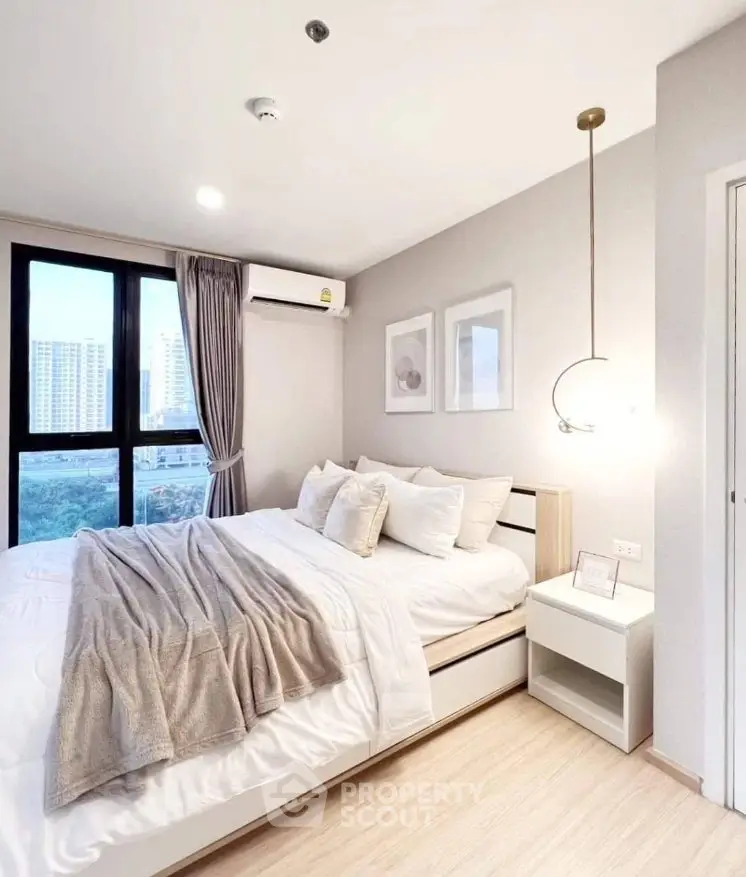 Modern bedroom with stylish decor and city view, featuring cozy bedding and elegant lighting.