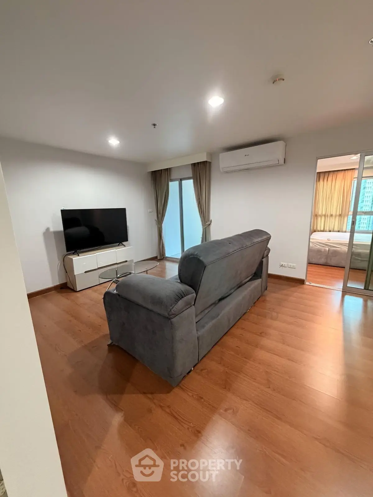 Spacious living room with modern decor and large TV, perfect for relaxation.