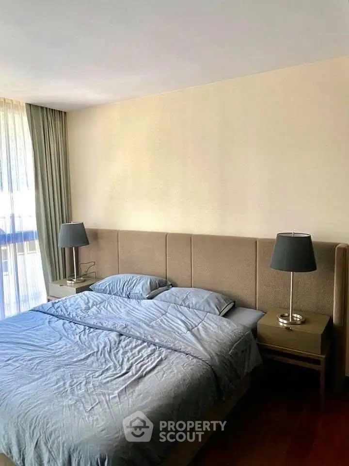Spacious bedroom with elegant decor and natural light, featuring a comfortable bed and stylish lamps.