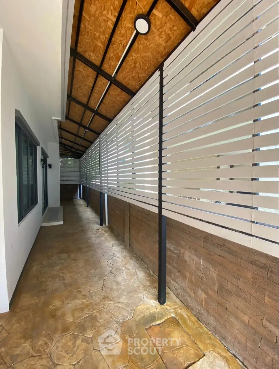 Modern covered walkway with stylish wooden ceiling and stone flooring in residential property.