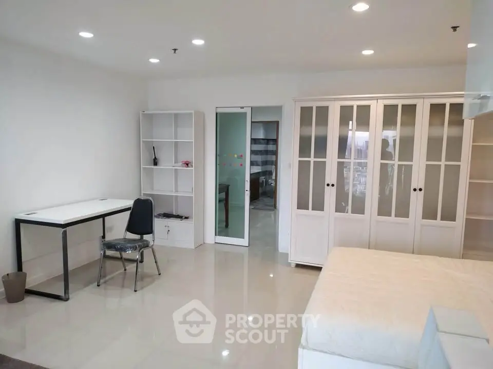 Spacious modern bedroom with sleek white furniture and ample storage space