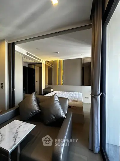 Modern studio apartment with stylish living area and cozy bedroom, featuring sleek furniture and large windows.