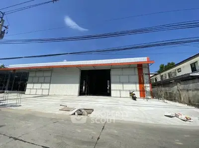 Spacious commercial warehouse with large entrance and ample parking space.