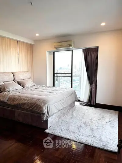 Luxurious bedroom with city view and elegant decor in high-rise apartment.