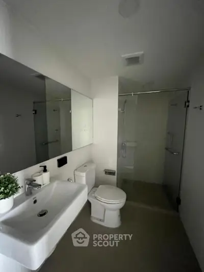 Modern bathroom with sleek design, featuring a glass shower enclosure and contemporary fixtures.