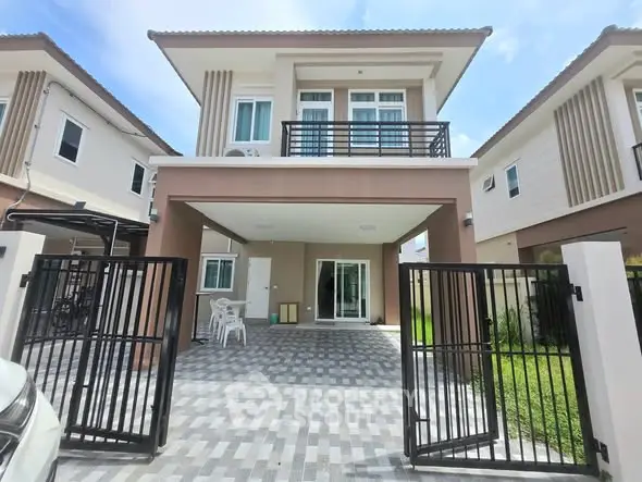 Modern two-story house with gated driveway and stylish facade in a suburban neighborhood.