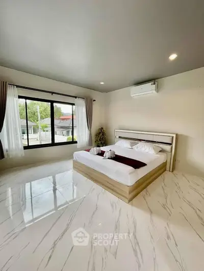 Spacious bedroom with large windows and modern decor in a stylish home.