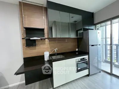 Modern kitchen with sleek cabinetry, built-in oven, and large fridge in a stylish apartment.