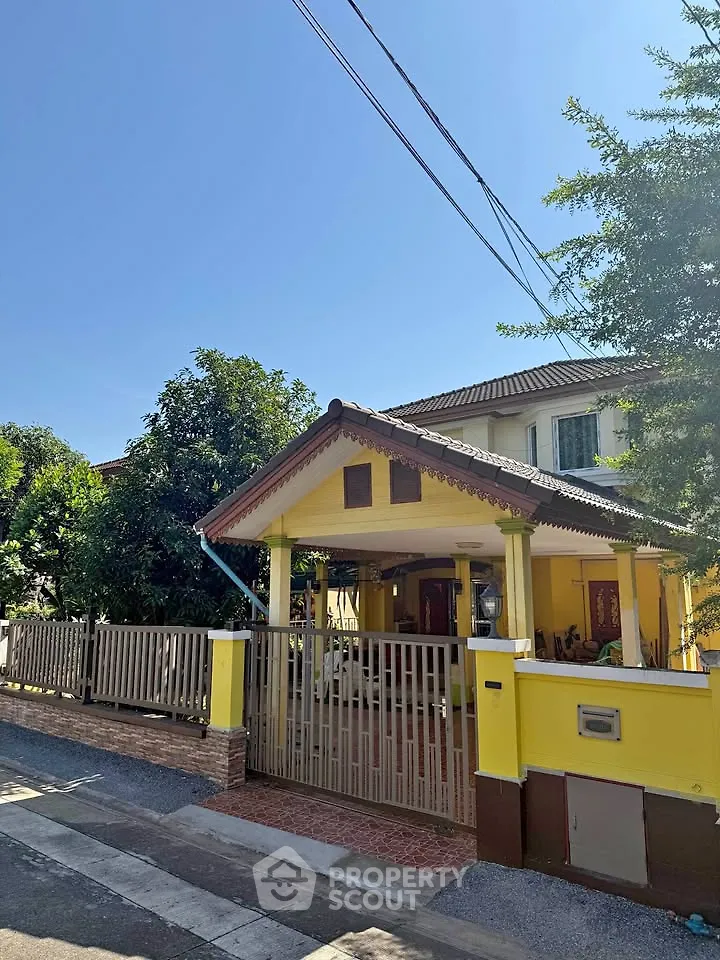 Charming yellow house with spacious front yard and gated entrance in sunny neighborhood.