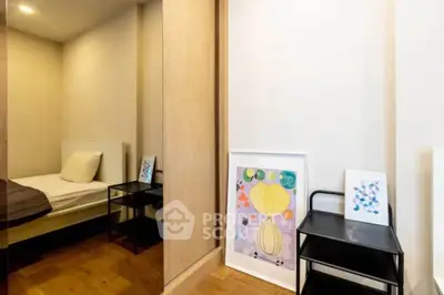 Cozy bedroom with modern decor and wooden flooring, featuring stylish artwork and sleek furniture.