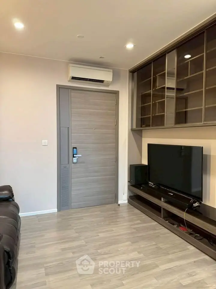 Modern living room with sleek TV setup and air conditioning, featuring stylish wooden flooring and built-in storage.