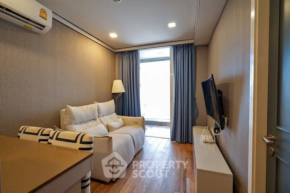 Cozy living room with modern decor and natural light, featuring a comfortable sofa and wall-mounted TV.