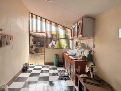 Spacious kitchen with open layout and checkered floor tiles, leading to an outdoor area.