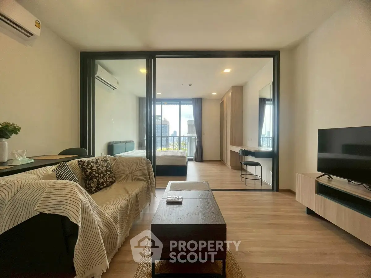 Modern open-plan living room with stylish decor and city view, featuring a cozy sofa and sleek TV setup.