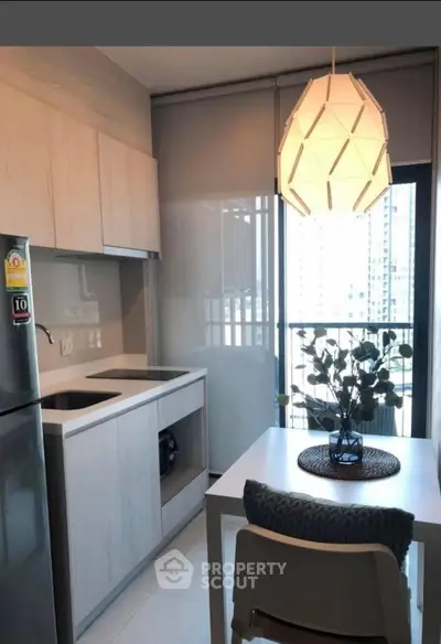 Modern kitchen with sleek cabinetry and dining area in a high-rise apartment.