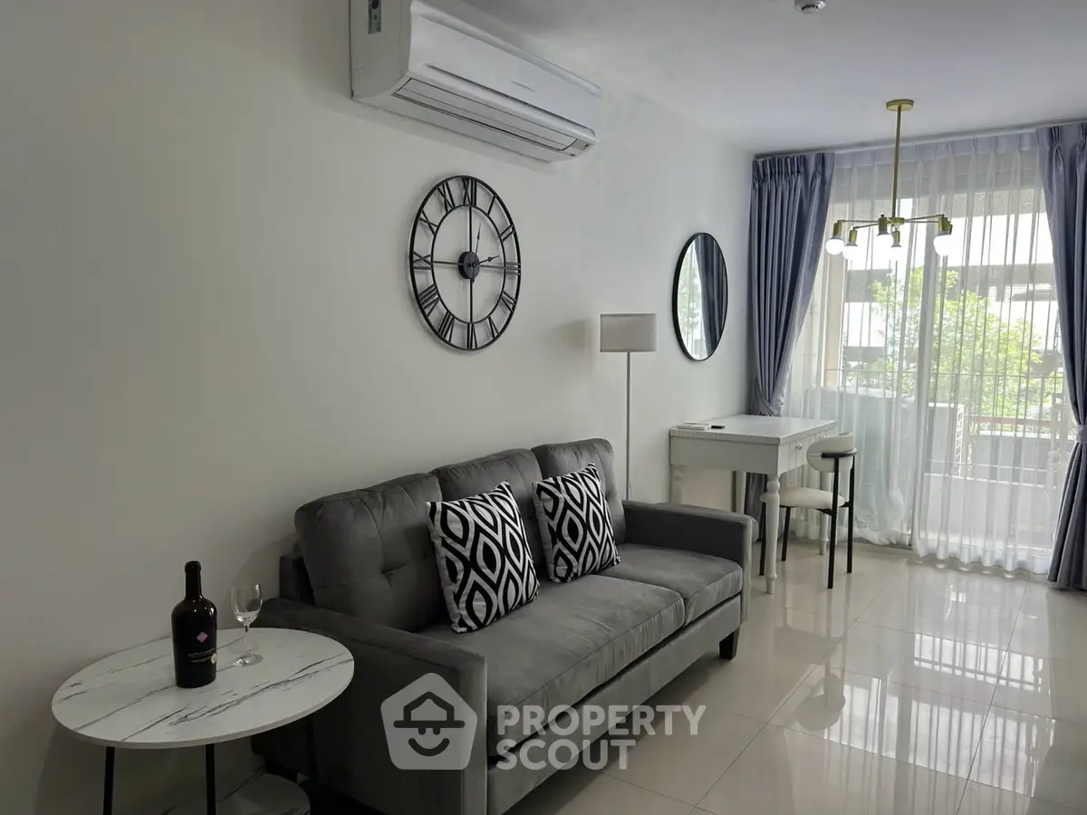 Modern living room with elegant decor, featuring a plush sofa, stylish clock, and natural light from large windows.