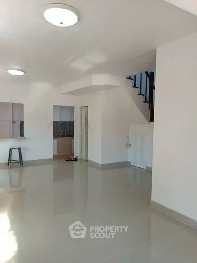 Spacious open-plan living area with modern tiled flooring and staircase.