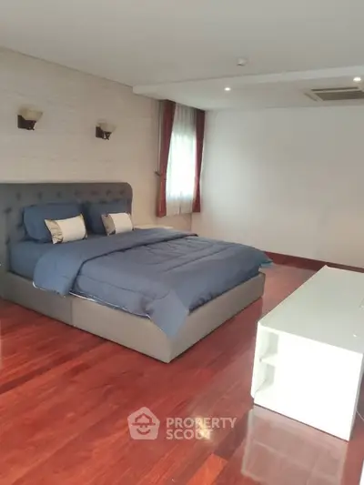 Spacious bedroom with elegant hardwood flooring and modern furnishings.