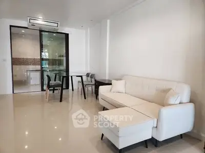Modern living room with white sofa and glass dining table in open layout.