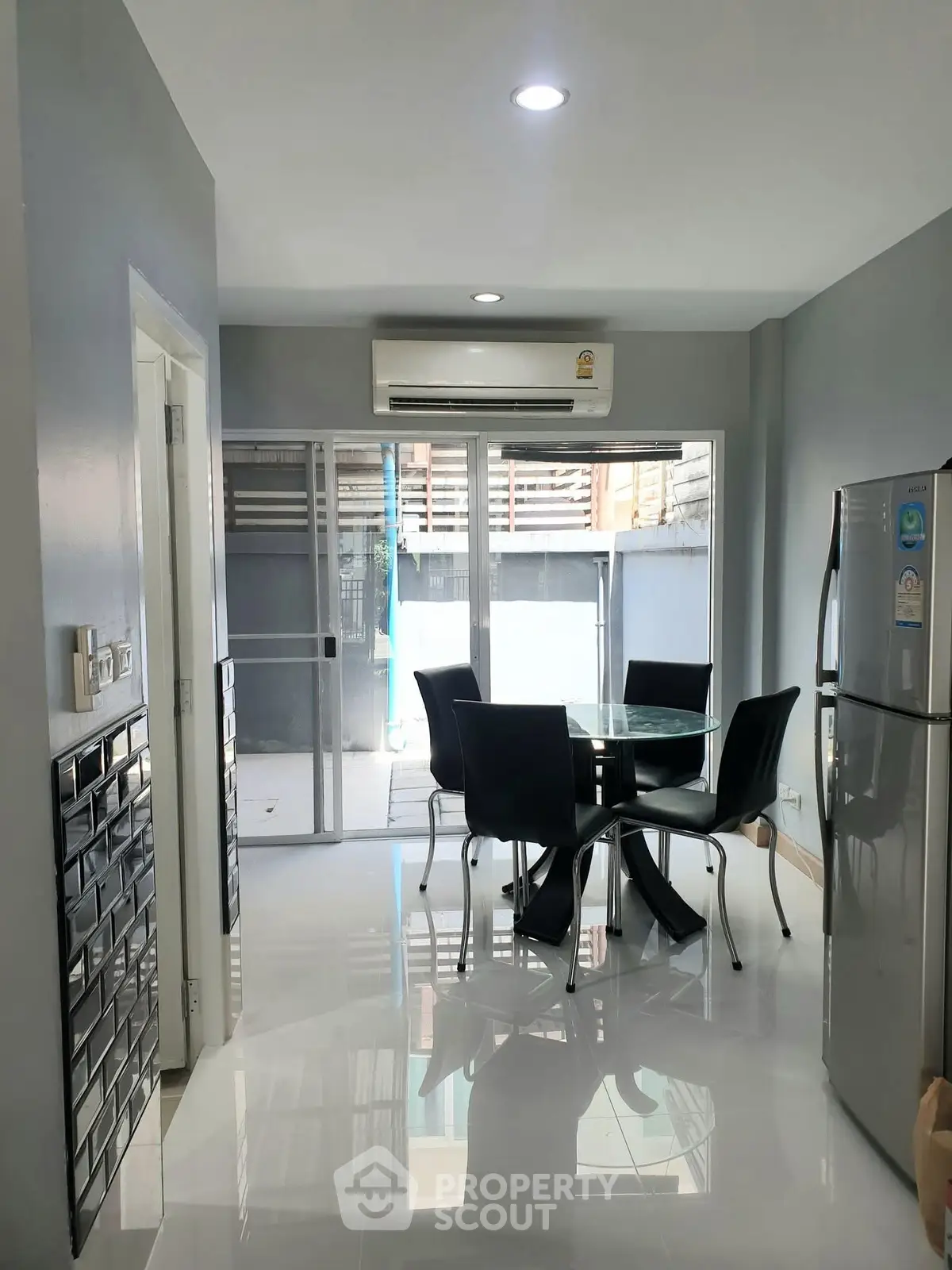 Modern dining area with sleek furniture and air conditioning, adjacent to a bright balcony.