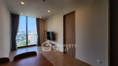 Modern living room with large window offering city view, wooden flooring, and minimalist decor.