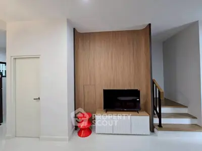 Modern living room with sleek TV setup and stylish red accent stool