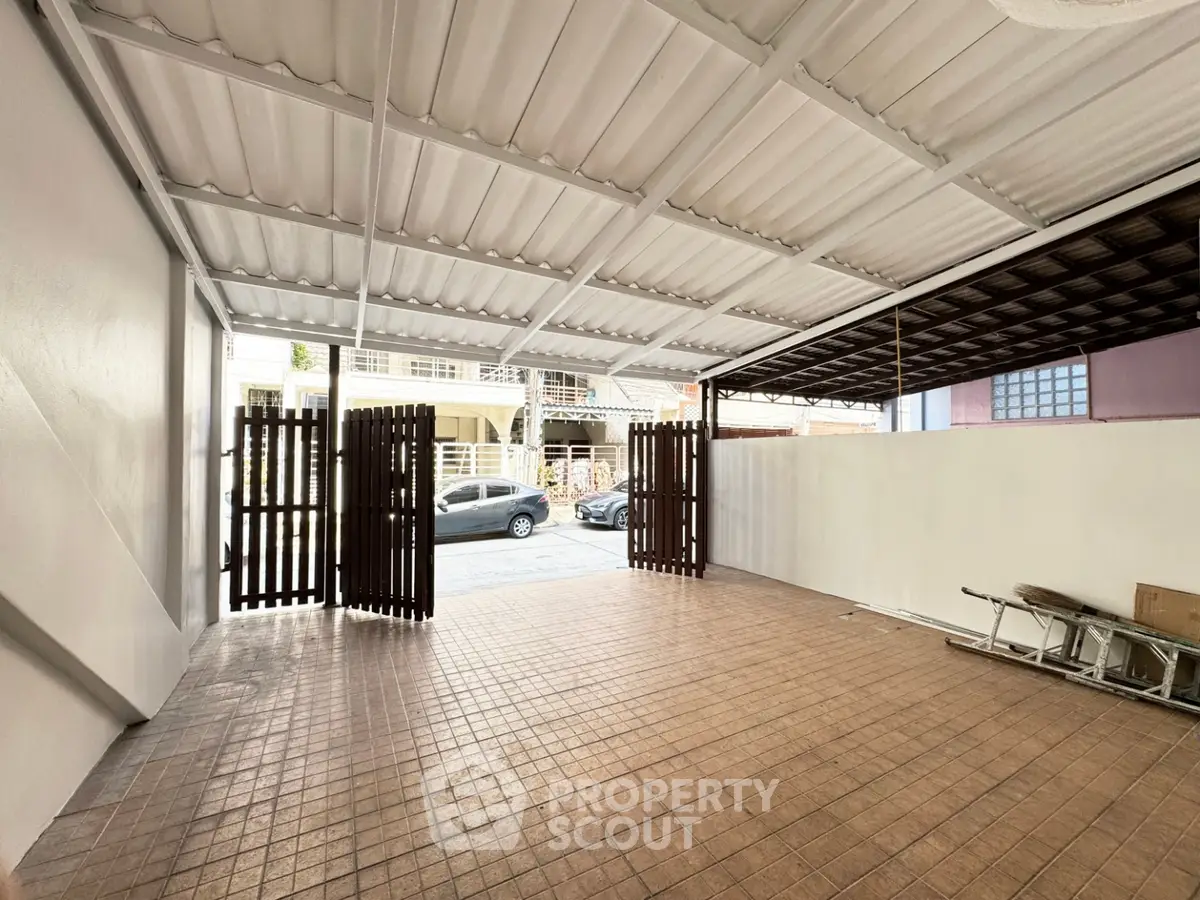 Spacious covered parking area with tiled flooring and wooden gate