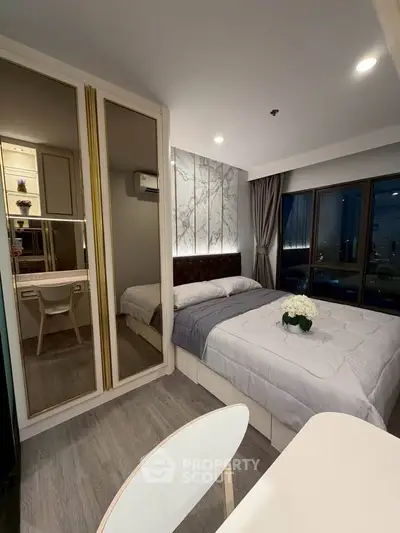 Modern bedroom with elegant decor and city view, featuring a cozy bed and stylish mirrored wardrobe.