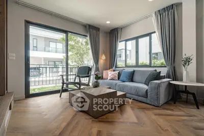 Modern living room with large windows and stylish furniture, offering a bright and inviting atmosphere.