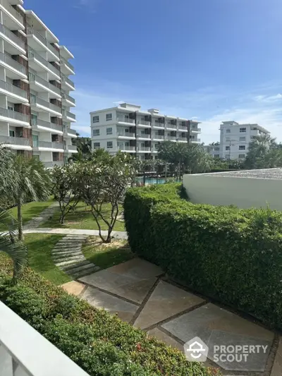 Modern apartment complex with lush gardens and clear blue sky view