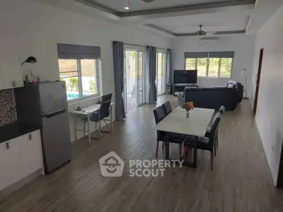 Spacious open-plan living and dining area with modern furnishings and pool view.