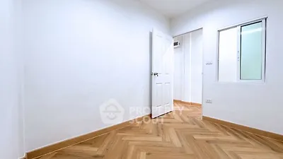 Spacious empty room with wooden flooring and white walls, perfect for customization.