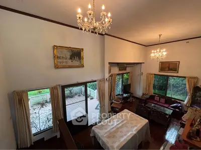 Elegant living room with high ceiling, chandelier, and garden view