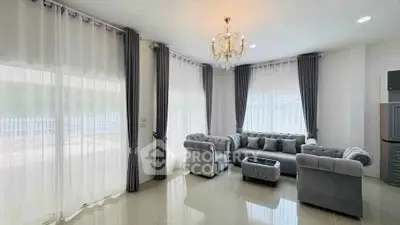 Elegant living room with plush gray sofas, chandelier, and large windows with sheer curtains.