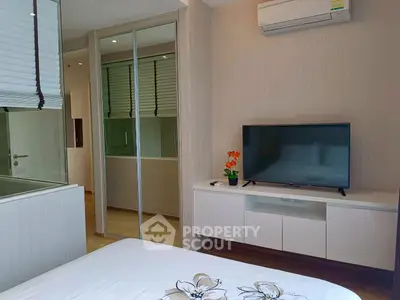 Modern bedroom with sleek design, featuring a wall-mounted TV and mirrored closet doors.