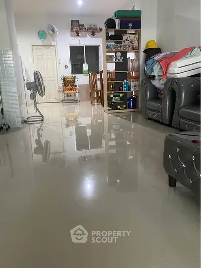Spacious living room with glossy tiled floors and modern furniture, perfect for family gatherings.