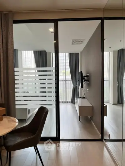 Modern living room with glass partition and sleek furniture in a high-rise apartment.