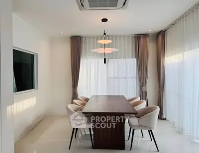 Elegant dining room with modern lighting and stylish chairs around a wooden table.