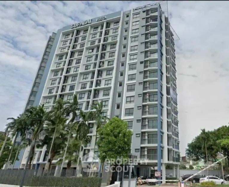 Modern high-rise building with lush greenery and clear sky view.