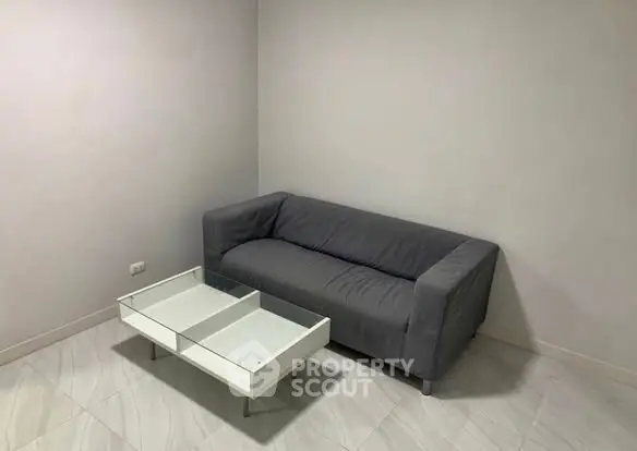 Minimalist living room with gray sofa and modern glass coffee table.