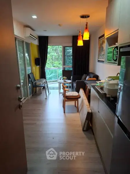 Modern living room with open kitchen and balcony view, featuring stylish lighting and contemporary decor.