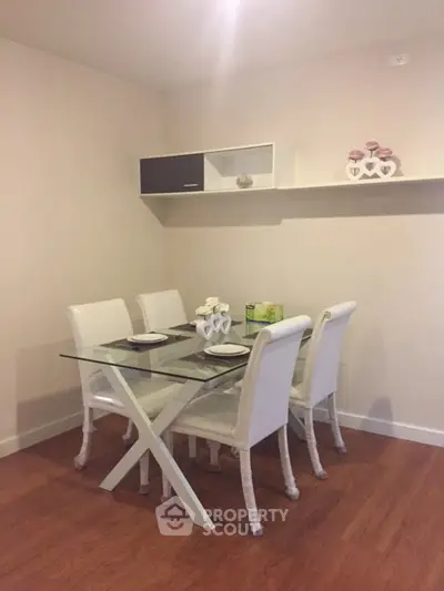 Modern dining area with glass table and white chairs in stylish apartment.
