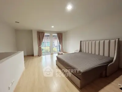 Spacious bedroom with elegant bed and balcony access, featuring natural light and modern design.