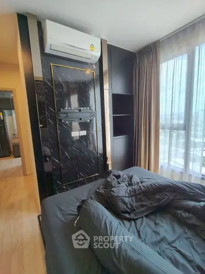 Modern bedroom with large windows and sleek air conditioning unit, featuring elegant black and gold accents.