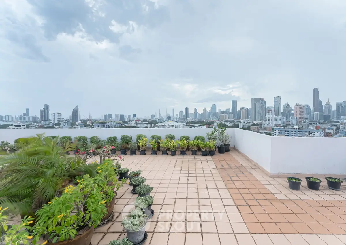 Stunning rooftop terrace with panoramic city skyline views and lush greenery.