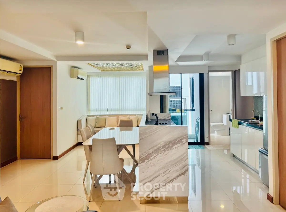 Modern open-layout living room and kitchen with elegant marble island and dining area.