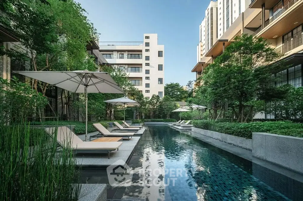 Luxurious apartment complex with serene pool and lush greenery, perfect for relaxation and modern living.