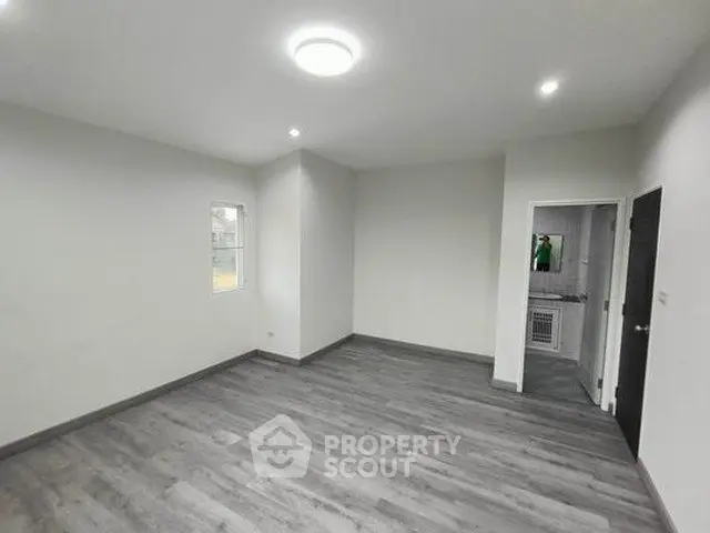 Spacious empty room with modern flooring and neutral walls, ideal for customization.